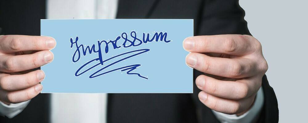 Mann hält Schild mit aufgemalter Schrift "Impressum"
